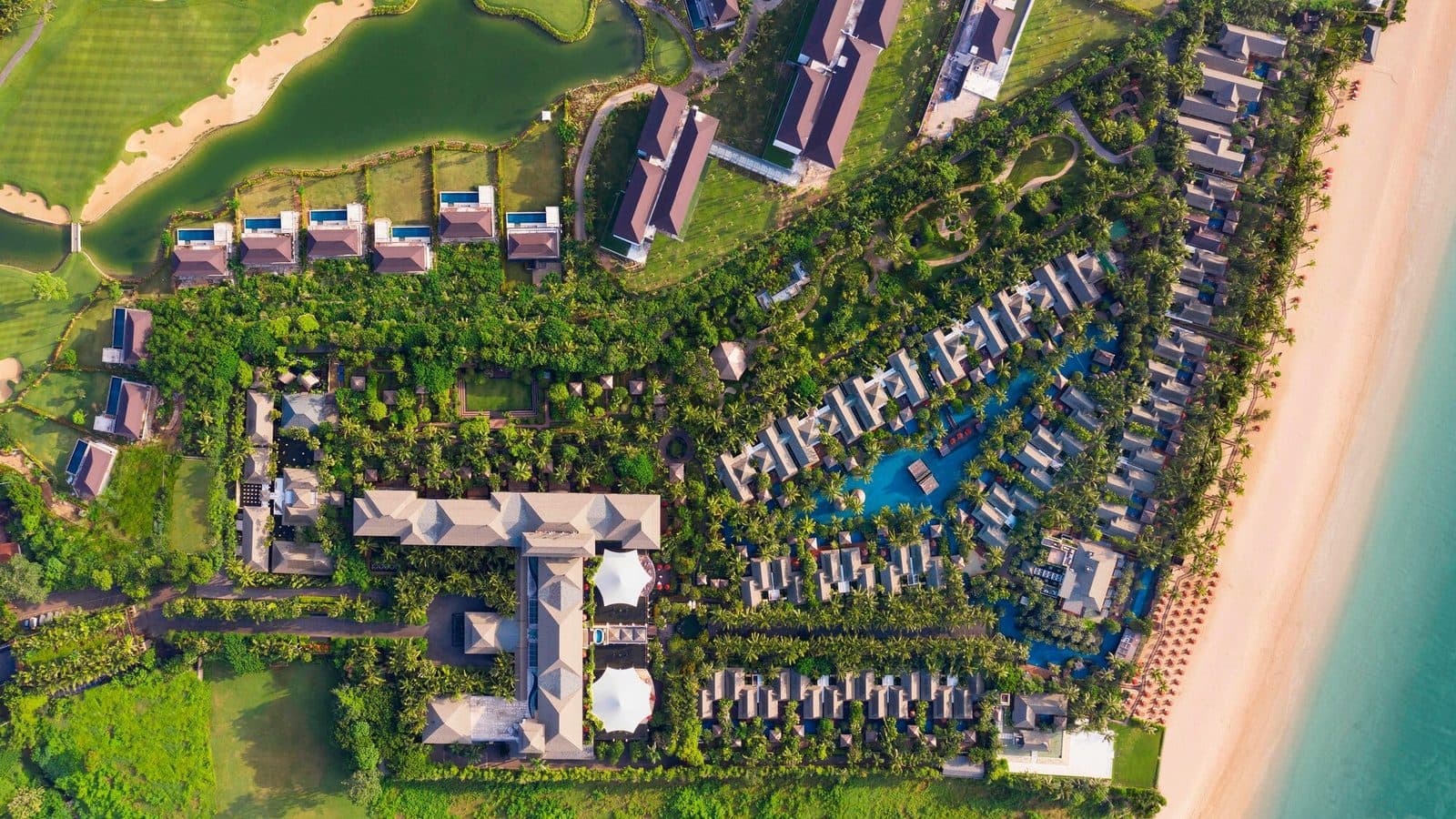 Вид сверху на The St. Regis Bali Resort: главное здание, виллы вокруг голубой лагуны, полоса пляжа вдоль океана и поле для гольфа с прудом
