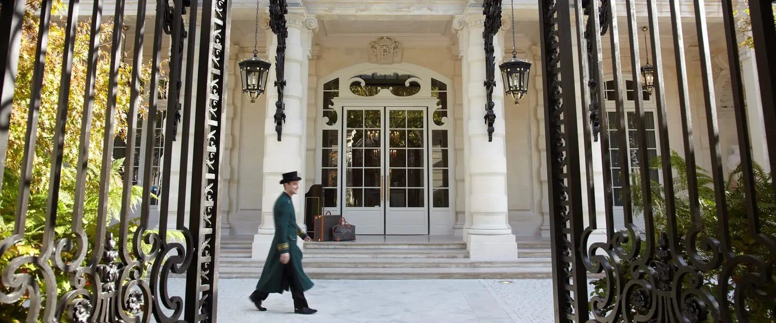 Вход в Shangri-La Paris за коваными воротами, у лестницы проходит сотрудник отеля