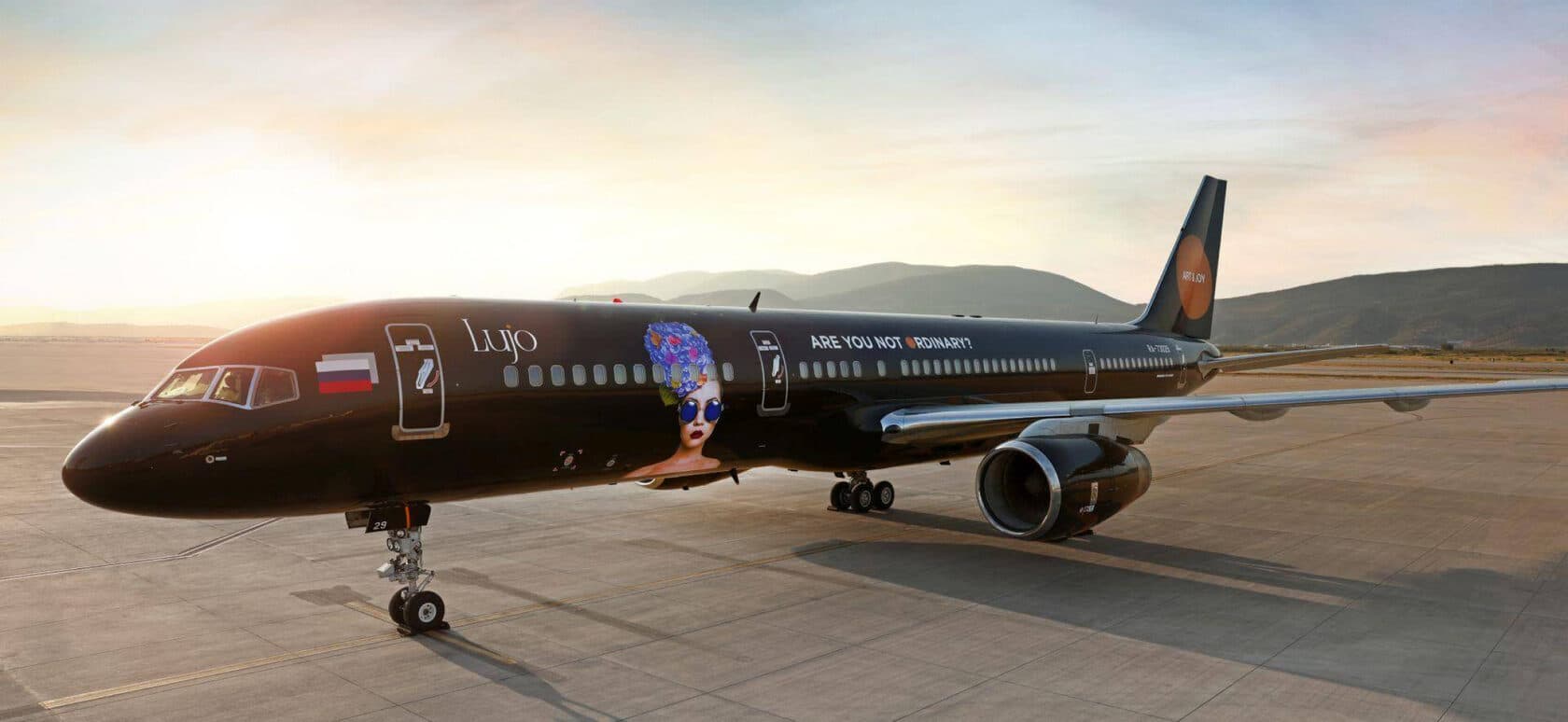 A black Lujo BlackJet Boeing 757-200 on the apron in evening light.