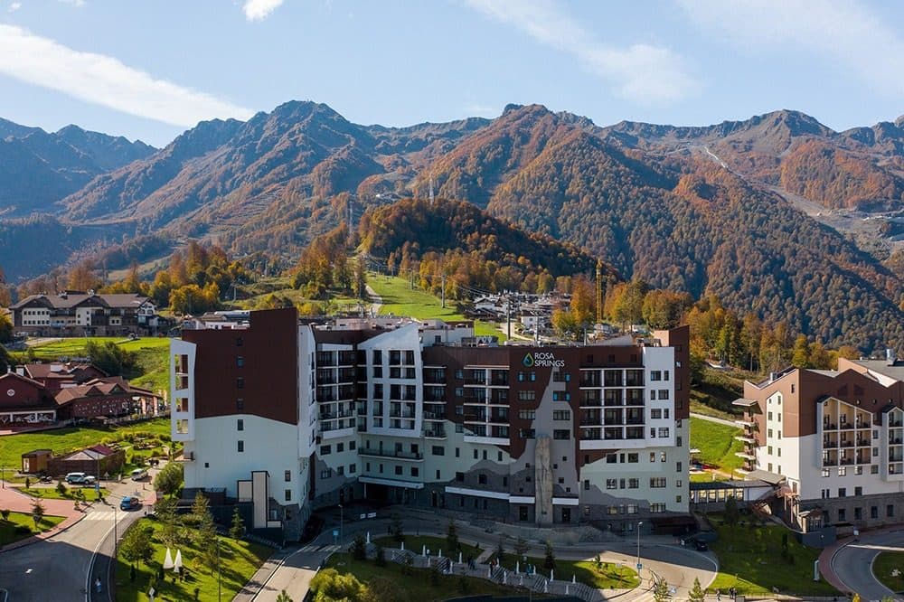 Корпус Rosa Springs в Горной Олимпийской деревне на фоне осенних гор