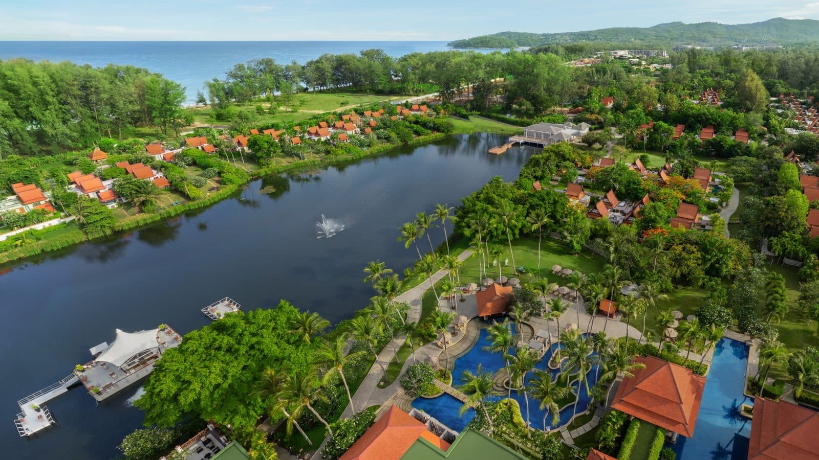Вид сверху на Banyan Tree Phuket: лагуна с плавучим павильоном, бассейны среди пальм, оранжевые крыши вилл и море на горизонте